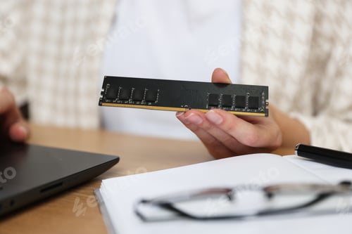 Preview: Memory drive. Woman with RAM module using laptop at wooden table indoors, closeup