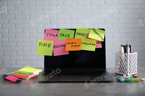 Preview: Laptop with colorful sticky notes and stationery on gray table indoors. Multitasking, deadline and r