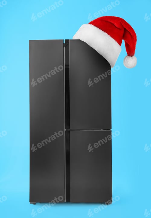 Preview: Fridge with red Santa hat on light blue background