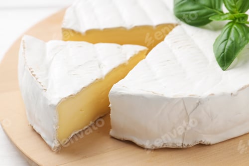 Preview: Cut delicious brie cheese and basil on white table, closeup