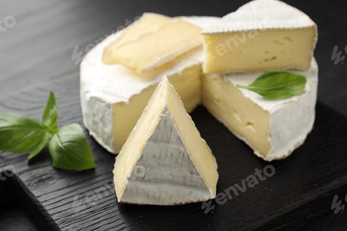 Preview: Slices of delicious brie cheese and basil on dark table, closeup