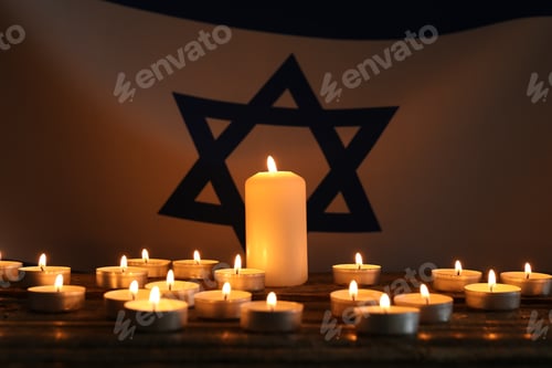 Preview: Holocaust Remembrance Day. Burning candles on table against flag of Israel, closeup