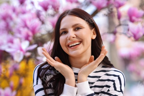 Preview: Beautiful woman in park with blossoming magnolia trees