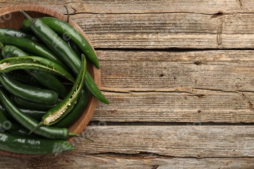 Preview: Fresh green chili peppers on wooden table, top view. Space for text