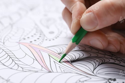 Preview: Woman coloring antistress picture with pencils at table, closeup