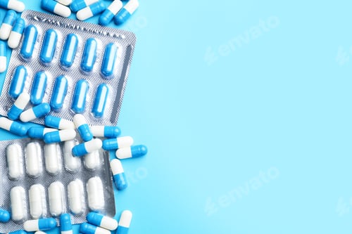 Preview: Many colorful pills on light blue background, flat lay. Space for text