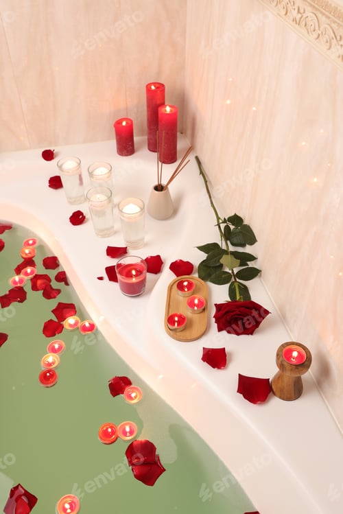 Preview: Romantic atmosphere. Bathtub with burning candles, petals, red rose and air reed freshener in bathro