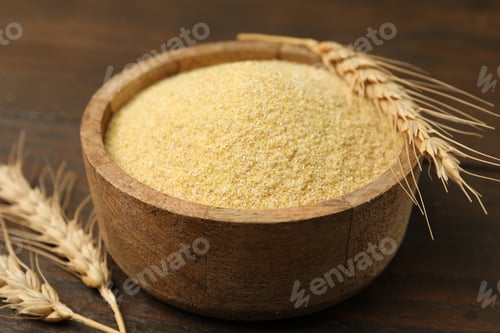 Preview: Raw semolina in bowl and spikes on wooden table, closeup