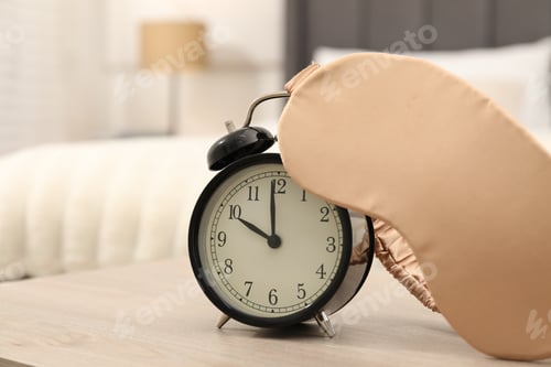 Preview: Alarm clock and sleep mask on wooden table in bedroom, closeup. Space for text