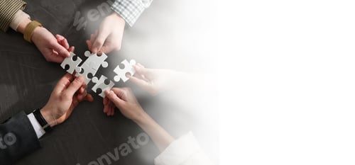 Preview: Team building. Coworkers joining puzzle pieces at table, top view. Space for text