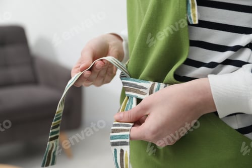 Preview: Woman tying clean apron at home, closeup