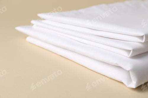 Preview: Bed linens on beige background, closeup. Space for text