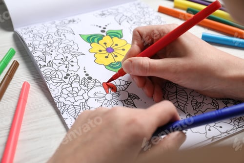 Preview: Woman coloring antistress picture with felt tip pen at white wooden table, closeup