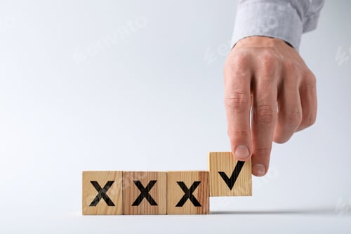 Preview: Man putting wooden cube with checkmark next to others with cross marks on table, closeup. Following