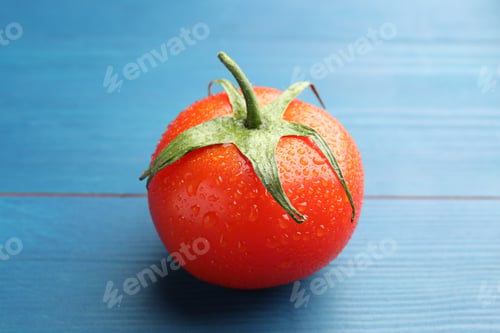 Preview: Ripe tomato with water drops on blue wooden table, closeup