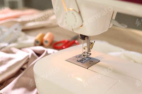 Preview: Sewing machine, fabrics and tools on table in workshop, closeup