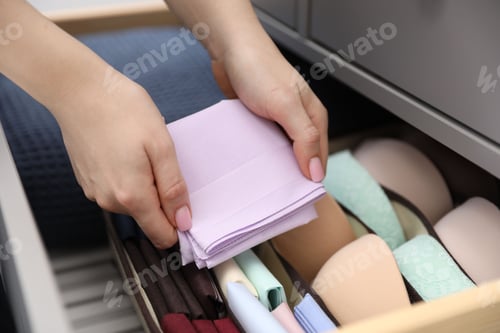 Preview: Woman putting handkerchief into drawer of dresser indoors, closeup