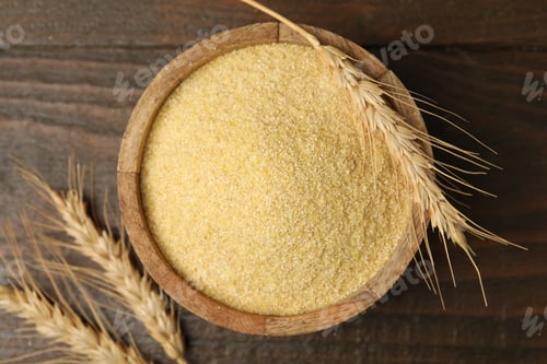 Preview: Raw semolina in bowl and spikes on wooden table, flat lay