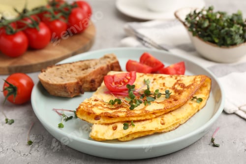 Preview: Tasty breakfast with omelette, microgreens, tomatoes and bread on grey table, closeup