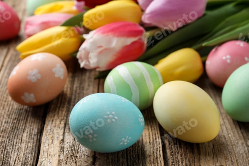 Preview: Painted Easter eggs and beautiful tulips on wooden table, closeup