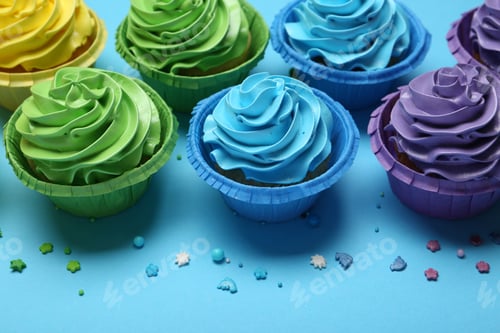 Preview: Many tasty cupcakes with bright cream and sprinkles on light blue background, above view