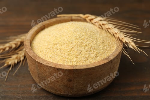 Preview: Raw semolina in bowl and spikes on wooden table, closeup