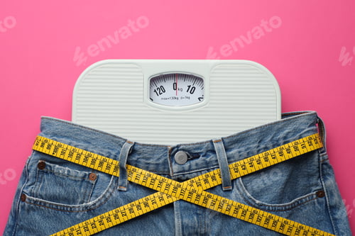 Preview: Jeans with measuring tape and scales on pink background, top view