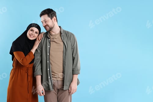 Preview: Portrait of happy muslim couple on light blue background. Space for text