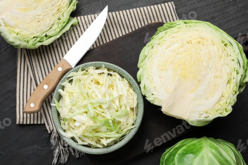 Preview: Fresh cabbages and knife on black textured table, flat lay