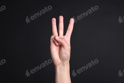 Preview: Man showing number three with fingers on black background, closeup