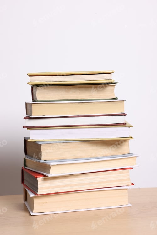 Preview: Stack of many books on wooden table against light background
