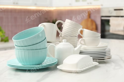 Preview: Different clean dishware on white table in kitchen