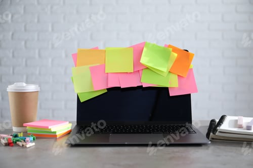 Preview: Laptop with colorful sticky notes, stationery and cup of coffee on gray table indoors. Multitasking,