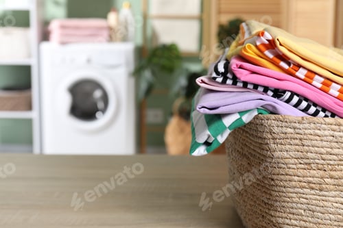Preview: Laundry basket with clothes on wooden table indoors, closeup. Space for text