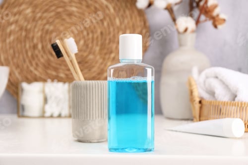 Preview: Bottle of mouthwash and toothbrushes on white table in bathroom