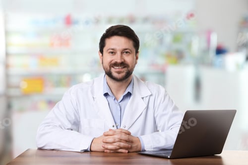 Preview: Pharmacist at table with laptop in drugstore