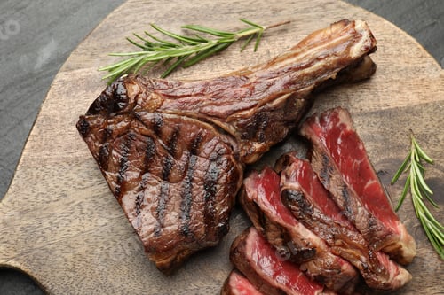 Preview: Pieces of tasty beef steak with rosemary on black table, top view