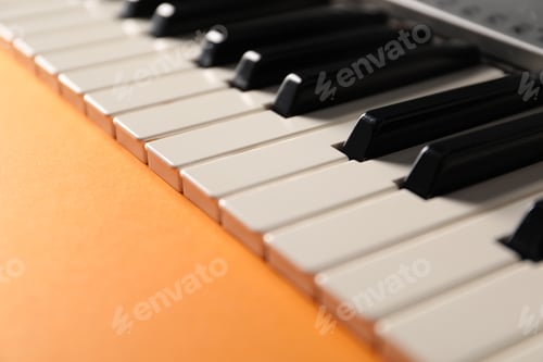 Preview: Piano keyboard on orange background, closeup. Musical instrument