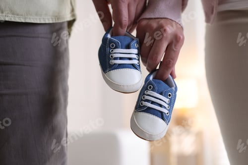 Preview: Couple with baby shoes at home, closeup