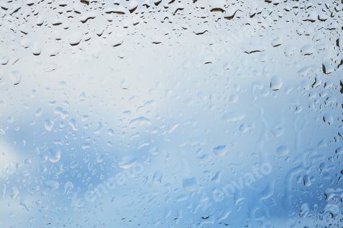 Preview: Window with water drops. View on blue sky with clouds through wet glass