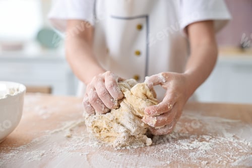 Preview: Child kneading dough at wooden table indoors, closeup