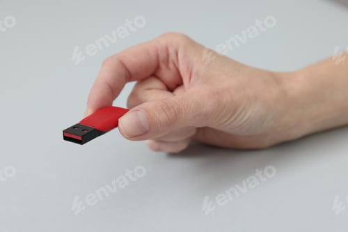 Preview: Woman with USB flash drive on light background, closeup