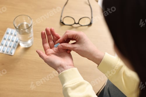 Preview: Woman with pill at wooden table indoors, above view