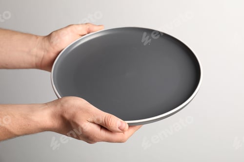 Preview: Man with empty plate on light grey background, closeup