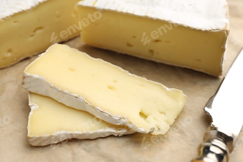 Preview: Cut delicious brie cheese and knife on table, closeup