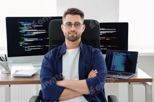 Preview: Happy young programmer working at desk in office
