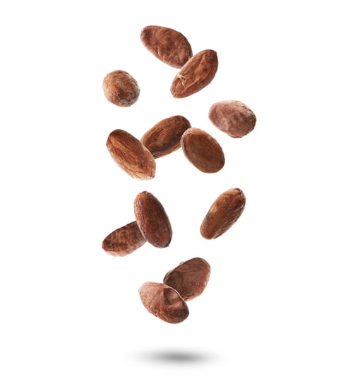 Preview: Many cocoa beans falling against white background