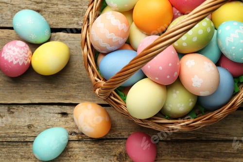 Preview: Easter basket with painted eggs on wooden table, flat lay