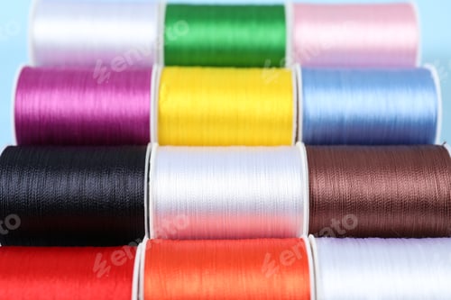 Preview: Spools of sewing threads on light blue background, closeup