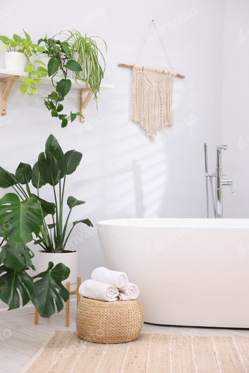 Preview: White bathtub, towels and green houseplants in stylish bathroom. Interior design
